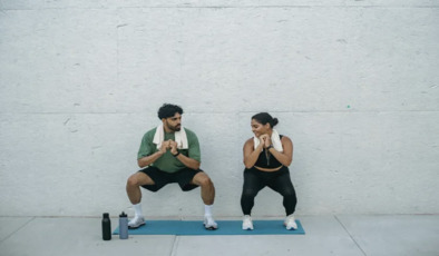 A man and a woman doing a body weight squat on a workout mat