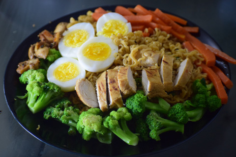 A salad with vegetables, chicken, and a boiled egg