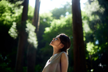 a woman is in a forest and is taking a deep breath