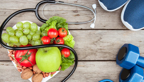 Fruit, vegetables and exercise equipment, arranged on a wooden floor.