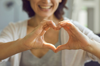 a woman is making a heart with her hands